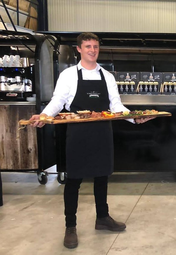 Daniël met een gevulde borrelplank bij de cateringwagen van Striethouldt Catering
